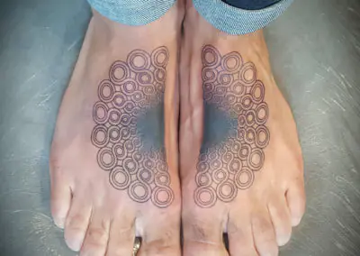 Tatouage mandala de cercles concentriques en dotwork sur les deux pieds