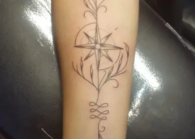Tatouage rose des vents en fine line avec ornements floraux