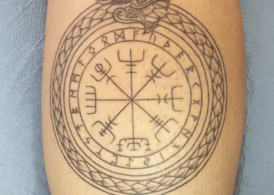 Tatouage vegvisir et runes nordiques cerclé d'un ouroboros sur le mollet